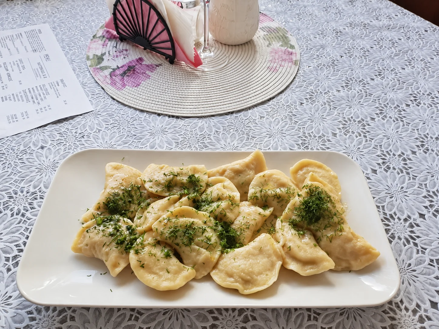 Pierogi posypane koperkiem na dużym talerzu